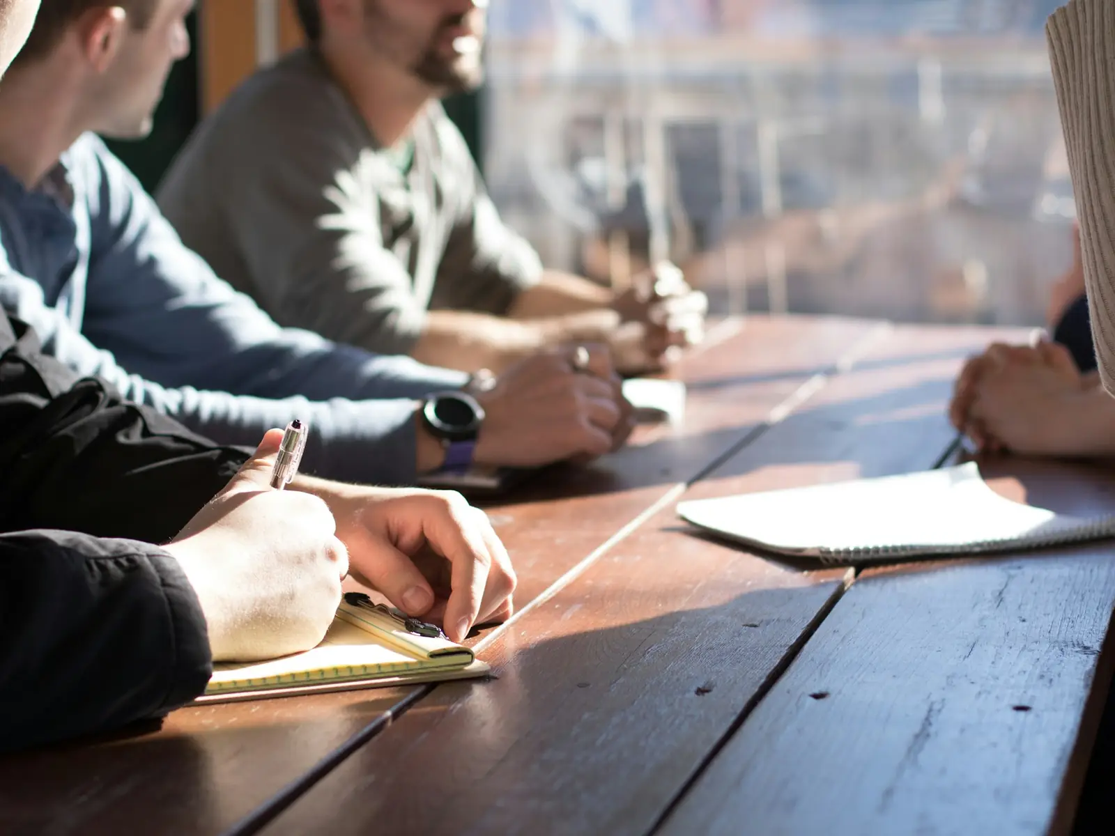 Colleagues around a meeting table, one taking notes